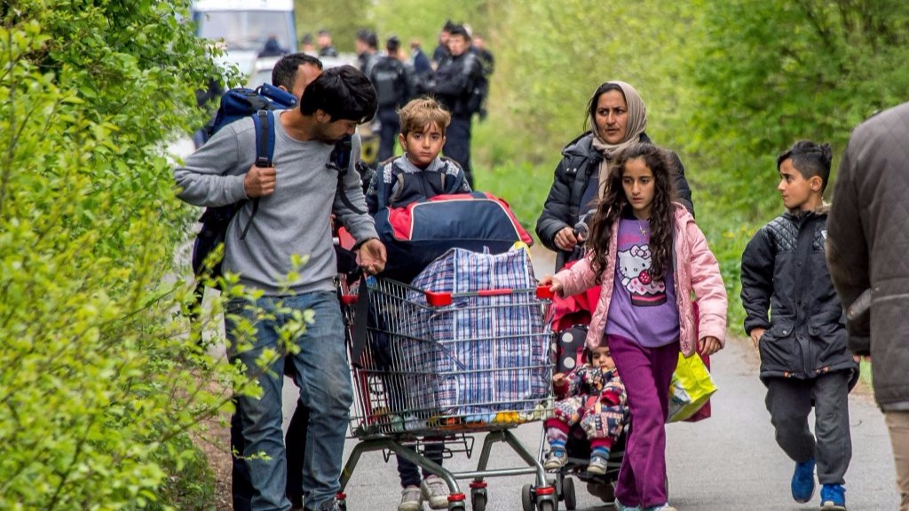 Migrants carry belongings while walking to board buses in Grande-Synthe, northern France, on April 14, 2017, as they leave a makeshift camp where around 300 migrants had found shelter after the destruction by a fire of their nearby camp, to head to reception and orientation centres. A huge fire gutted one of France's biggest migrant camps housing 1,500 people, which started after a brawl involving hundreds of Afghans and Kurds late on April 10. The Grande-Synthe facility near the northern French port of Dunkirk was the only one in the area and provided hundreds of wooden huts for shelter, as well as cooking facilities and showers